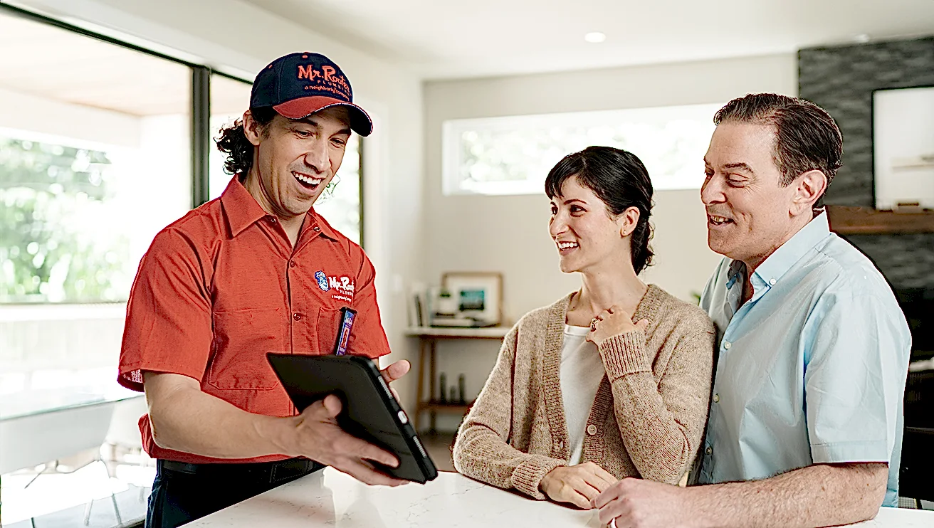 Mr. Rooter technician showing customers service options on a tablet.